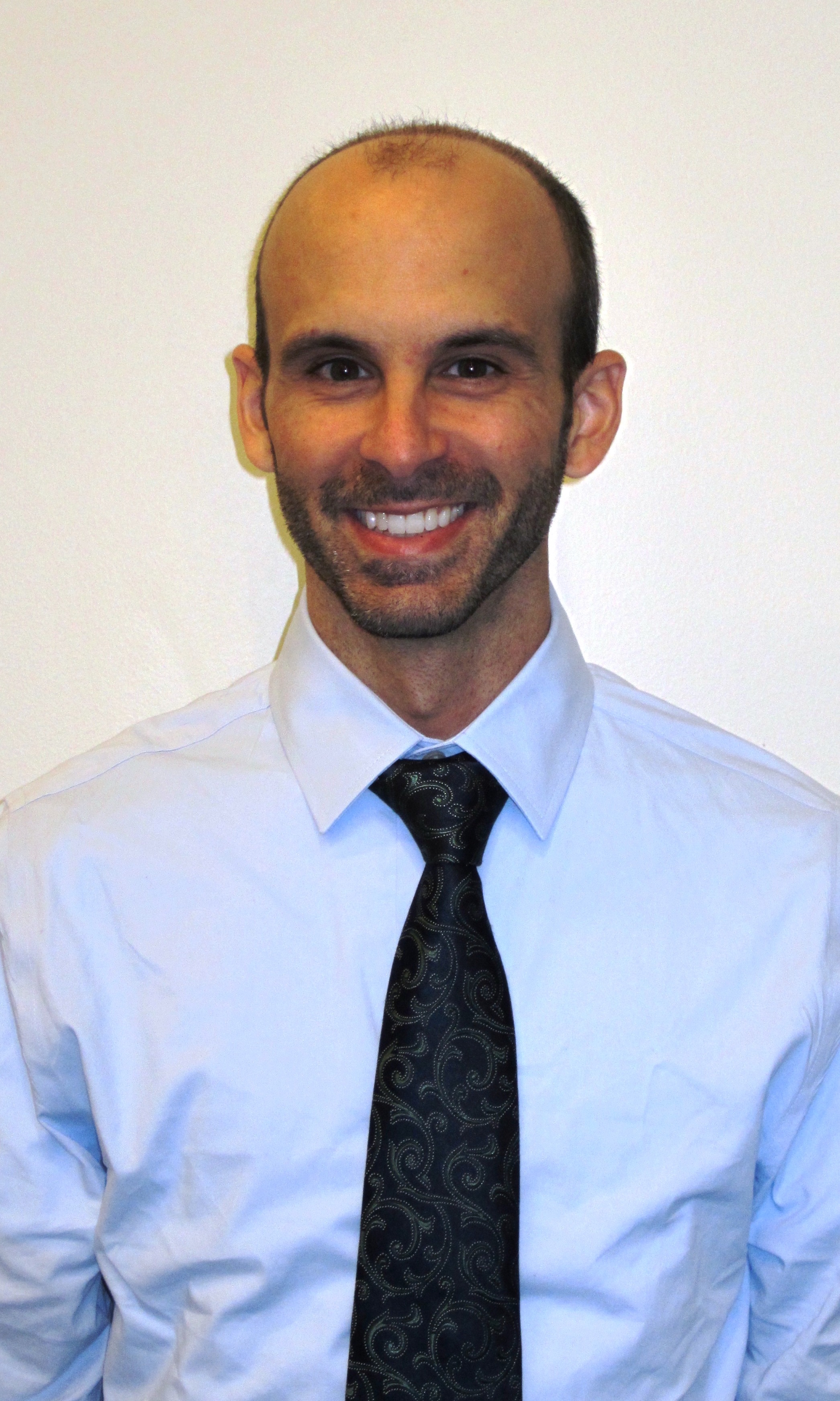 Bio headshot photo of Dr.Brian A. DiGangi, smiling, wearing a blue shirt and dark tie